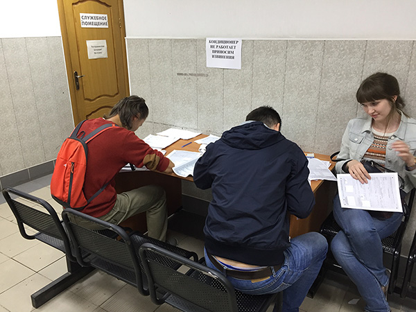 Люди заполняют бланки регистрации в ФМС Санкт-Петербурга